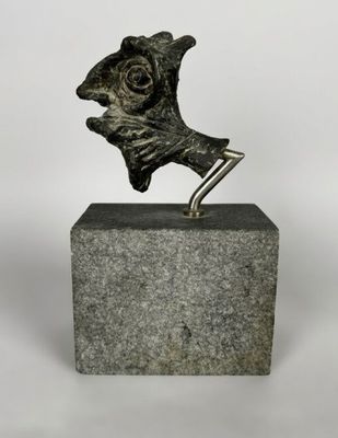 une sculpture en bronze représentant un chien posé sur un socle, sur fond blanc