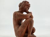 a small wooden statue of a man sitting on a rock