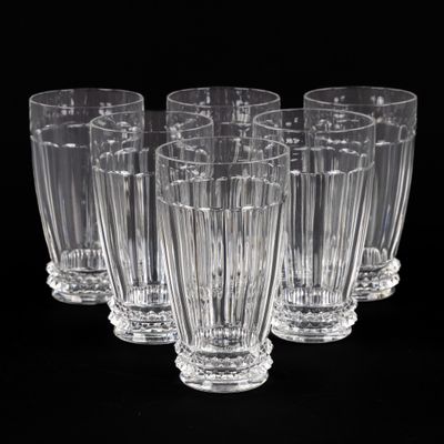 six verres transparents sont alignés en rangée sur une surface noire