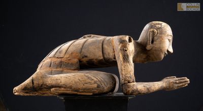 une image représentant une statue en bois d'un homme à genoux sur un socle