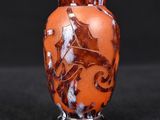 an orange vase with a horse on it on a black surface