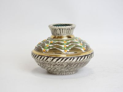 a silver and gold vase sitting on a white surface