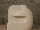 a white sculpture on a wooden bench in front of a brick wall