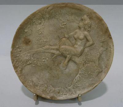une assiette blanche sur laquelle est représentée une femme assise sur une branche d'arbre