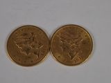 two gold coins sitting on a white surface