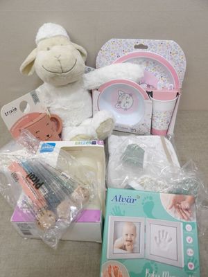 un mouton en peluche posé à côté d'une boîte contenant des articles pour bébé