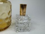 a bottle of perfume next to a glass bottle with a gold cap