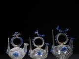 four glass vases with blue and white designs on them on a black surface