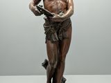 bronze statue of a man holding a book on a pedestal