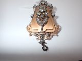 a gold and silver brooch on a white surface