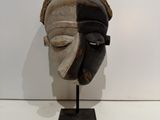 an image of a wooden mask on a stand on a white surface