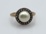 a close up of a ring with a pearl and black diamonds