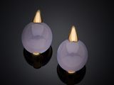 a pair of white jade and gold earrings on a black surface