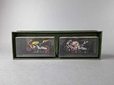 two miniature motorcycles in a green box on a white surface