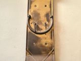 a clock hanging on the wall with a metal handle