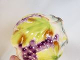 a hand holding a vase with grapes painted on it