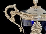 a silver and blue vase with a lid on a stand