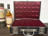 une valise noire doublée de velours rouge et une bouteille de whisky