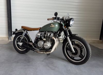 une moto verte garée dans un garage, à côté d'une porte de garage