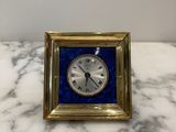a small clock sitting on a marble counter top