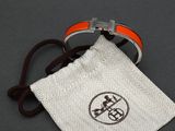 an orange and white bracelet with a silver buckle and a white pouch