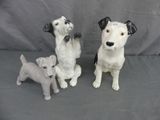 trois figurines de chiens assis sur une surface grise