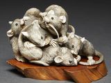 a statue of a group of mice sitting on a piece of wood
