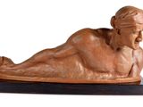 statue of a woman laying on her stomach on a wooden base