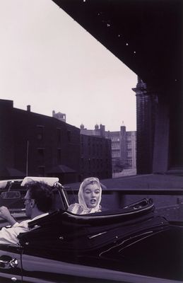 black and white photograph of two women in a convertible car on a city street