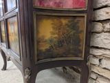 a cabinet with a painting on it next to a stone wall