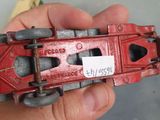 a hand holding a red toy truck with a sticker on it