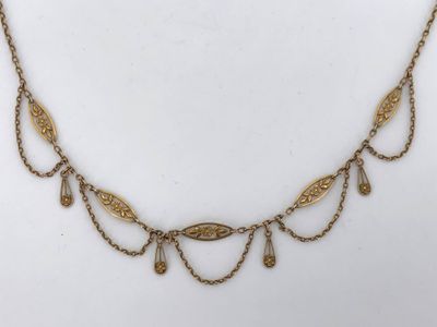 a gold necklace with a leaf design on a chain