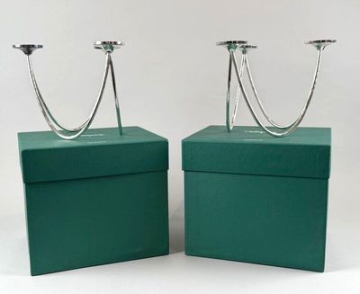 pair of silver candlesticks in a green box on a white background