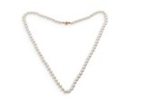 un collier de perles blanches avec un fermoir en or sur fond blanc