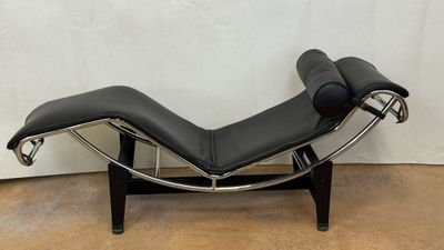 a black leather chaise lounger sitting on a wooden floor