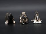 three figurines of animals sitting on a black surface