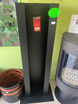 un poêle noir posé à côté d'une plante en pot, sur le sol