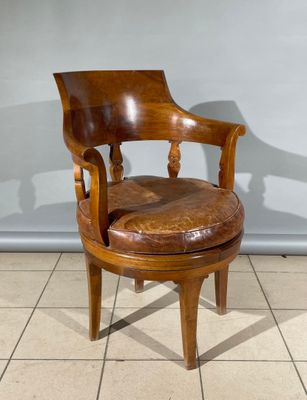 une photo d'une chaise en bois avec une assise en cuir, posée sur un sol carrelé
