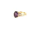 a close up of a gold ring with a purple stone