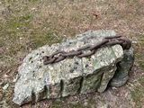 a large rock with a chain on it in the grass