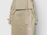 a beige trench coat hanging on a white wall