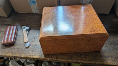 une petite boîte en bois contenant un couteau et un repose-couteau, posée sur une table