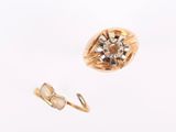 a gold ring with a flower on it next to a pair of earrings