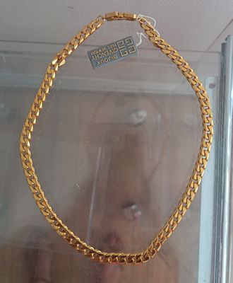 someone is taking a picture of a gold necklace in a glass case