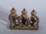 three figurines of three people sitting on a bench
