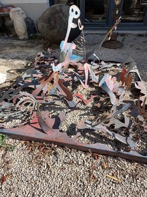 une sculpture métallique représentant un squelette posé sur un tas de ferraille