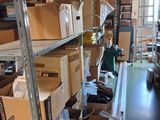des cartons sont empilés sur une étagère dans une pièce où se trouve une échelle