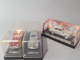 three die cast cars in plastic cases sitting on a table