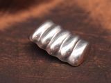 un petit objet en argent posé sur un tissu marron