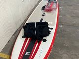 une planche de surf rouge et blanche sur laquelle est posé un sac noir